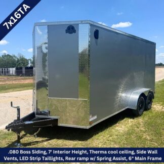 Silver enclosed cargo trailer with tandem axles and diamond-plate front, labeled model 7x16TA. Has a rear ramp, side vents, and sits on a grassy lot.
