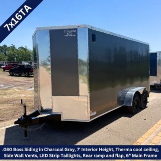 Enclosed dual-axle utility trailer with charcoal gray siding, chrome diamond-plate front, and a tongue hitch ready for towing