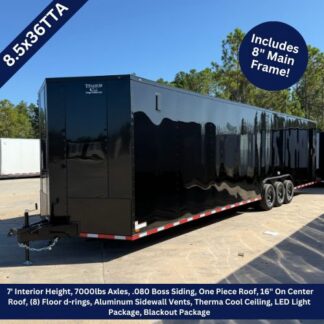 Titanium Cargo 8.5×36 Black Triple Axle Enclosed Cargo Trailer with Black Out Package ‣ Boss Cargo Trailers Long glossy black enclosed trailer on a dirt lot under a clear blue sky; features banners note 8.5x36TA and 7' interior height, 7000 lb axles, aluminum sidewalls, LED lighting, and an 8' main frame included.