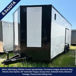 Enclosed tandem-axle cargo trailer on a grassy lot, black front and white sides with a hitch at the tongue.